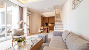 Ein modernes Wohnzimmer mit einer Couch, einem Couchtisch und einem Topfpflanzen. Eine Treppe führt zu einer oberen Ebene.