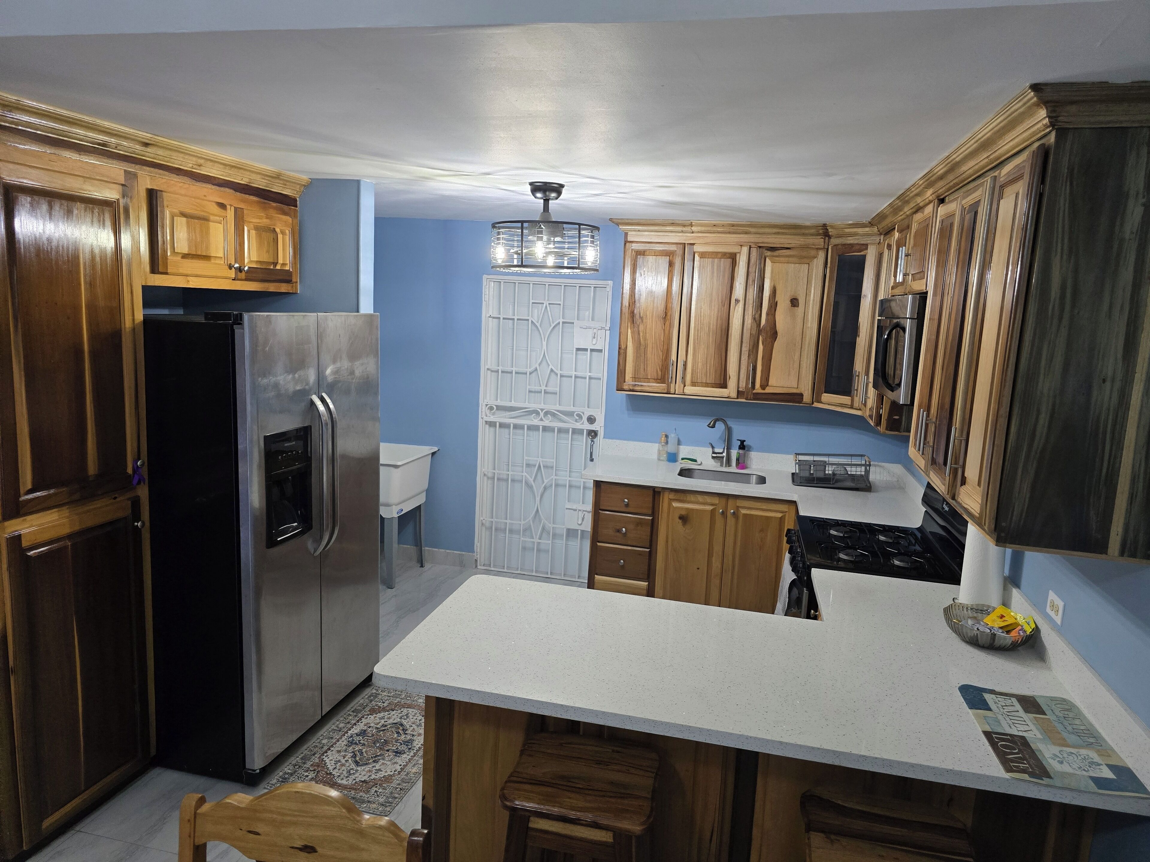A kitchen with wooden cabinets, a stainless steel refrigerator, a microwave, and a gas stove.