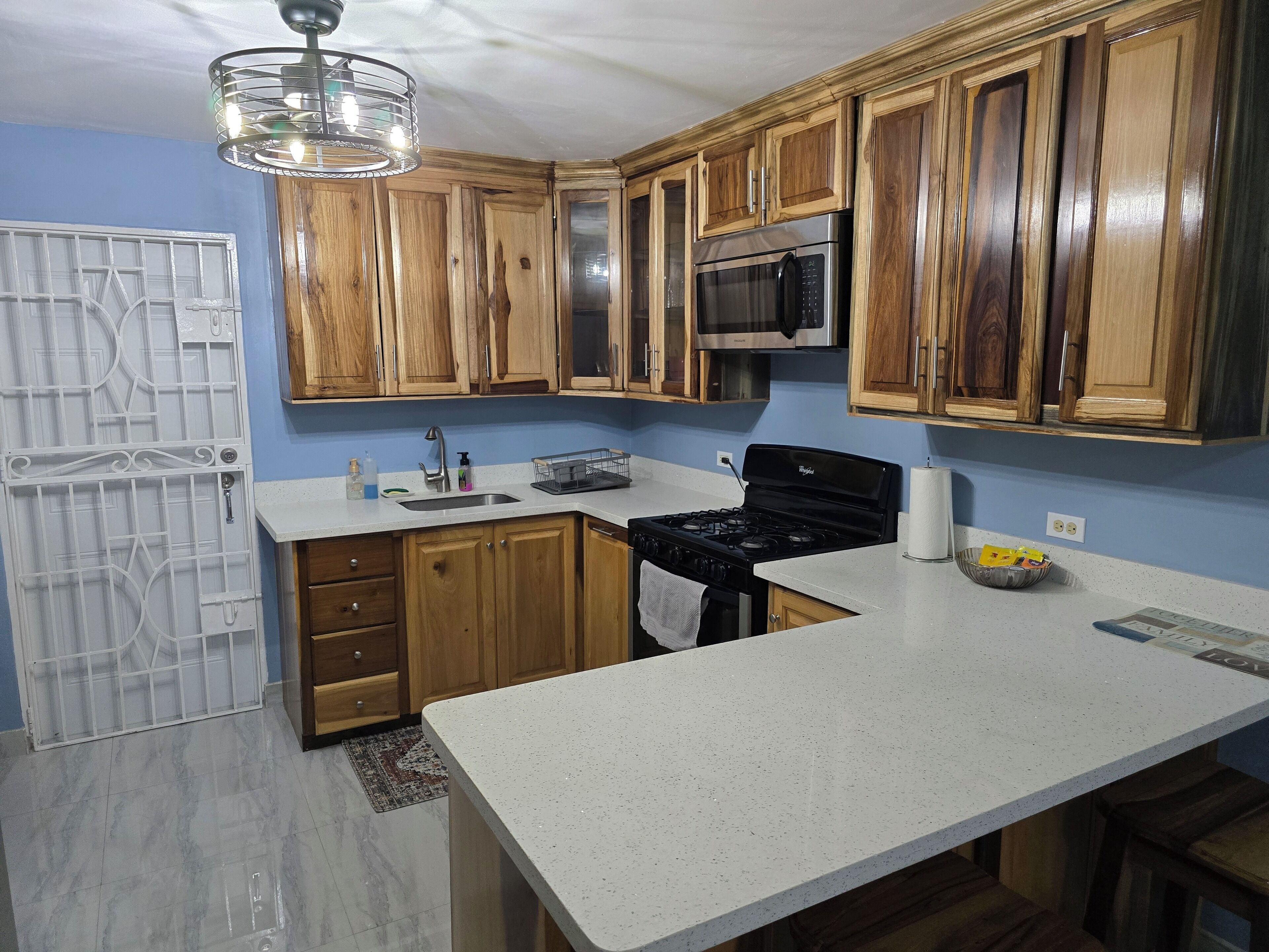 A kitchen with wooden cabinets, a stainless steel microwave, a stove, and a sink.
