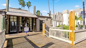 A beachfront property with a wooden deck, a gated entrance, and a sign indicating a key drop-off point.