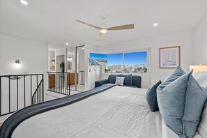Un dormitorio moderno con una cama grande, un ventilador de techo y vistas a la ciudad a través de una ventana.