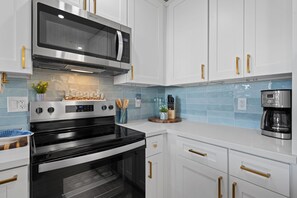 Una cocina moderna con electrodomésticos de acero inoxidable, armarios blancos y una cafetera.