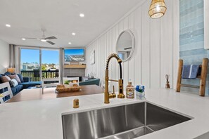 A modern kitchen with a stainless steel sink, a unique gold faucet, and a large window overlooking a scenic view.