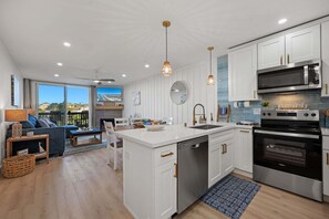 A modern kitchen with white cabinetry, stainless steel appliances, and a large island.