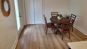Un comedor con una mesa redonda de madera, cuatro sillas de madera y una planta en maceta sobre la mesa.