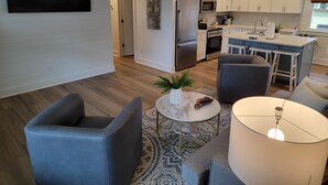 Una cocina moderna con armarios blancos, electrodomésticos de acero inoxidable y una isla central con taburetes.