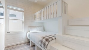 Un dormitorio con cama, ventana y ventilador de techo.