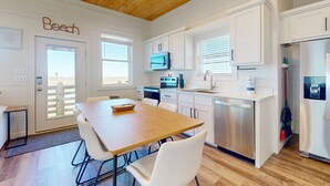 Una cocina moderna con armarios blancos, techo de madera y vistas al exterior.