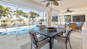 An outdoor patio with a pool, dining table, chairs, and ceiling fans. - Lakefront view with Pool & Spa, large Patio, close to Beaches and Shopping! Monthly Discount (Fort Myers)