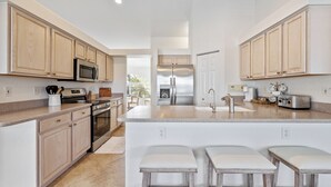 A modern kitchen with wooden cabinets, stainless steel appliances, and a central island with bar stools. - Lakefront view with Pool & Spa, large Patio, close to Beaches and Shopping! Monthly Discount (Fort Myers)