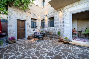 A stone courtyard with a wooden door, a table with chairs, and potted plants. - Yamak Stone House (Urgup)