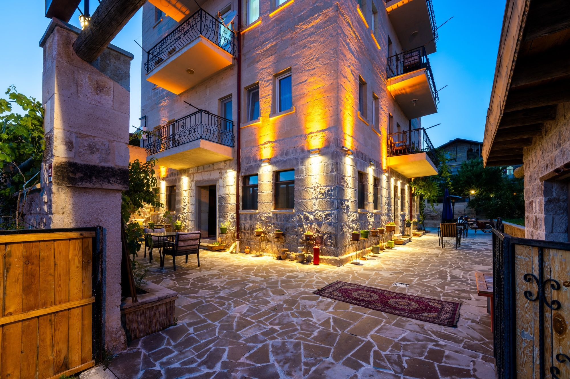 A multi-story building with stone facade, outdoor seating area, and a gated entrance.