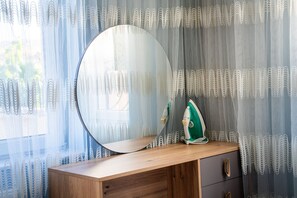 A wooden vanity with a round mirror and a green iron on top. - Yamak Stone House (Urgup)