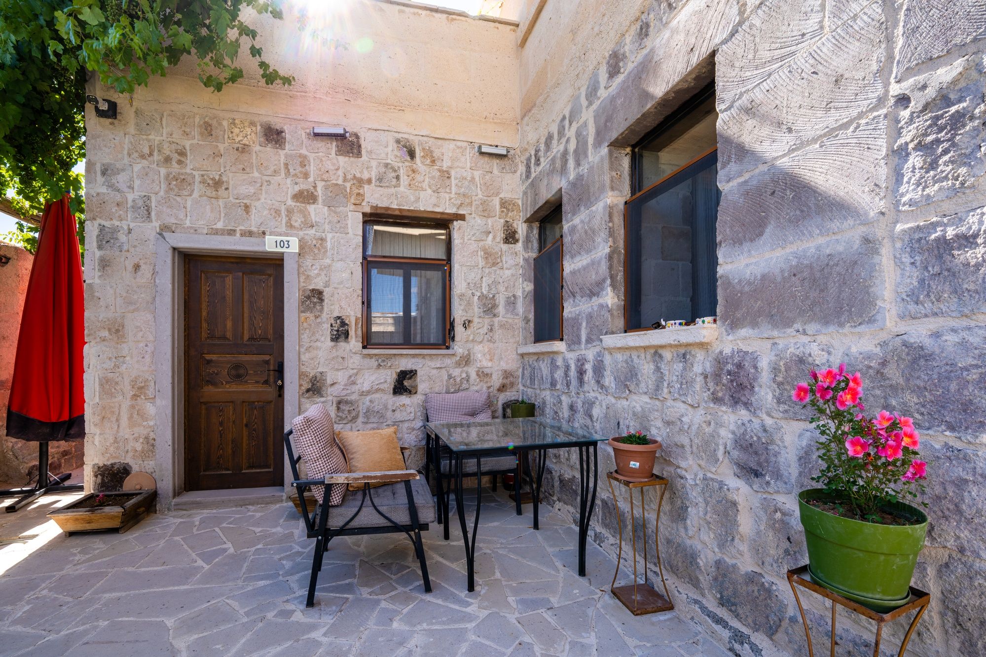 A stone building with a wooden door, a window, and a table with chairs.