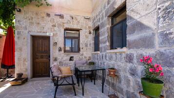 Un edificio de piedra con puerta de madera, una ventana y una mesa con sillas.