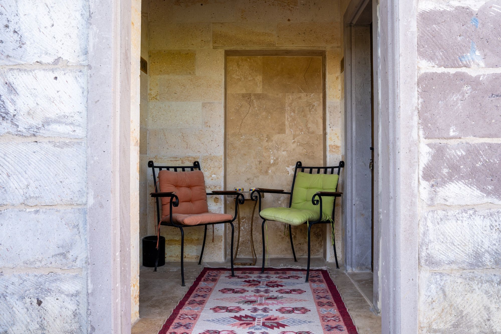 A narrow corridor with two chairs and a patterned rug.