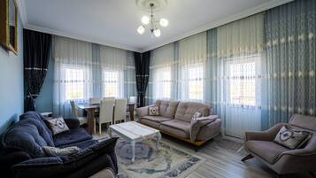 A living room with a sofa, armchair, coffee table, and a dining table with chairs.