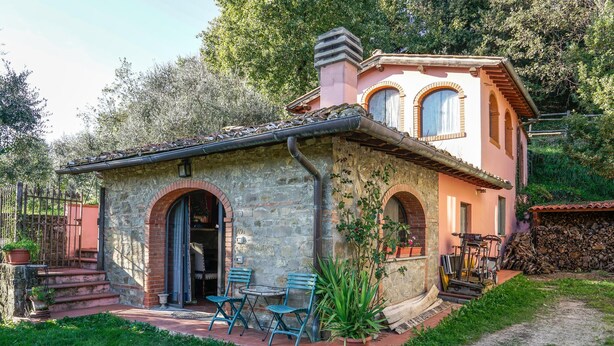 A stone house with a pink facade, two arched windows, and a small porch with a table and chairs. - Amazing apartment in Reggello with WiFi (Reggello)