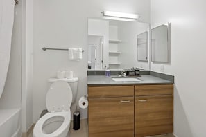 A modern bathroom with a toilet, sink, and vanity. - Tysons 1BR + Queen Den | High Floor Views & Pool (Tysons)