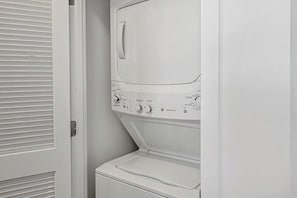 A white wall-mounted washer and dryer unit with control knobs and a door handle. - Tysons 1BR + Queen Den | High Floor Views & Pool (Tysons)