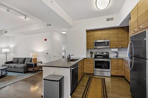 A modern kitchen with wooden cabinets, stainless steel appliances, and a central island. - Tysons 1BR + Queen Den | High Floor Views & Pool (Tysons)