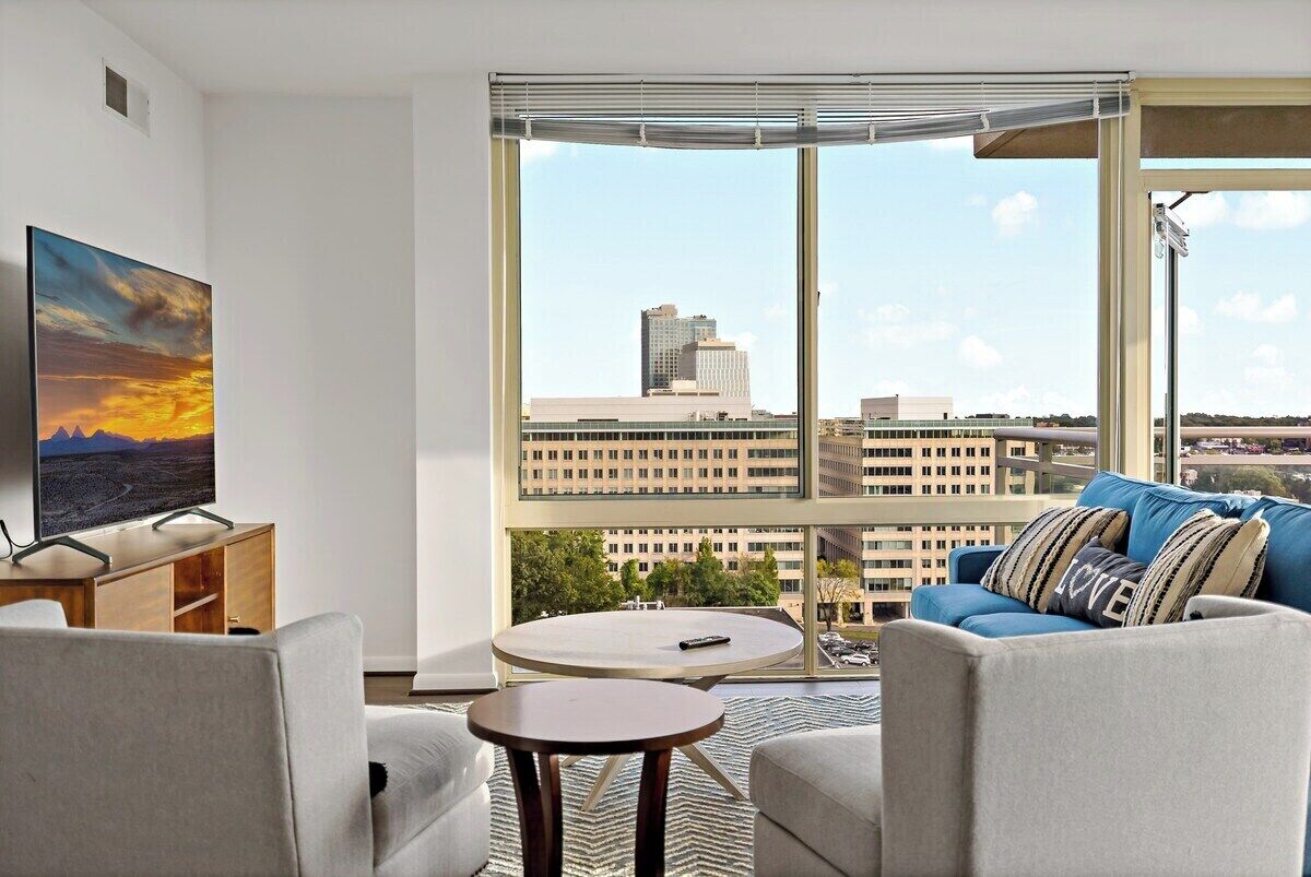 A modern living room with a large window, a flat-screen TV, a sofa, and a coffee table.