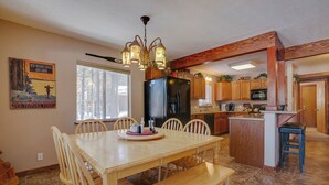 A spacious kitchen with a dining area, featuring a large island, wooden cabinets, and a chandelier.