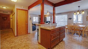 A spacious kitchen with a large island, wooden beams, and a dining area with a table and chairs.