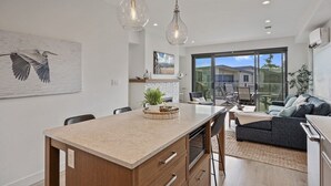 A modern kitchen with a central island, pendant lighting, and a dining area with a sofa and chairs. - Sea and Ski at The Beach House (Black Creek)