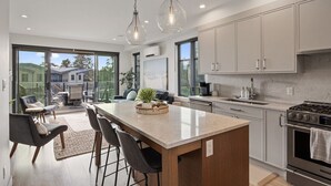 A modern kitchen with a large island, stainless steel appliances, and a view of the outdoors. - Sea and Ski at The Beach House (Black Creek)