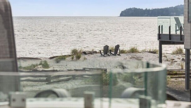 A beach view from a room with a control panel in the foreground, a glass railing, and two chairs on the sand. - Sea and Ski at The Beach House (Black Creek)