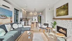 A modern living room with a grey sofa, wooden coffee table, and a fireplace. - Sea and Ski at The Beach House (Black Creek)