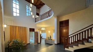 Un hall d’entrée spacieux avec un plafond haut, un escalier et un espace détente.