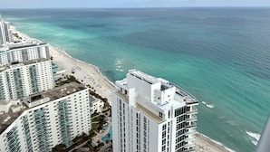 A high-rise hotel with a beach view, multiple balconies, and a swimming pool.