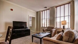 A living room with a flat-screen TV, a coffee table, a sofa, and a lamp. - One bedroom at Baltimore Covention Ctr (Baltimore)