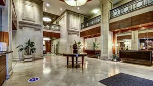 A spacious lobby with a marble floor, a reception desk, and a staircase leading to an upper level. - One bedroom at Baltimore Covention Ctr (Baltimore)