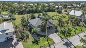 A residential area with multiple houses, including a two-story house with a balcony and a garage. - Bokeelia Bliss! 3/3 Heated Pool, Boat Ramp Included! (Bokeelia)