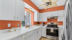 A kitchen with white cabinets, a stainless steel oven, and a ceiling fan. - Bokeelia Bliss! 3/3 Heated Pool, Boat Ramp Included! (Bokeelia)