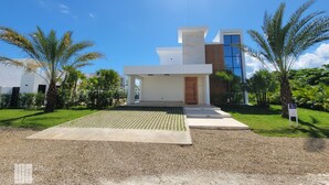 A modern villa with a spacious patio, palm trees, and a clear blue sky. - Villa Marina (Sosúa)