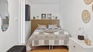 Une chambre à coucher comprenant un lit, des tables de chevet, un miroir et des éléments de décoration murale.