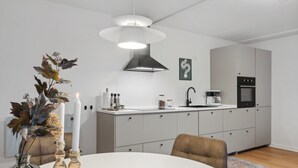 Une cuisine moderne avec un plan de travail blanc, une hotte noire et un four encastré.