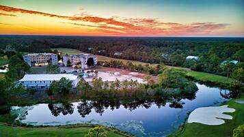 Un hotel grande con varias construcciones, un campo de golf y un lago.