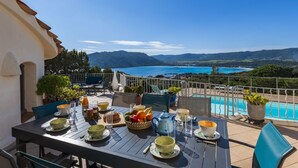 A terrace with a table set for breakfast overlooking a pool and scenic mountains. - Villa Sallena by Interhome (Porto Vecchio)