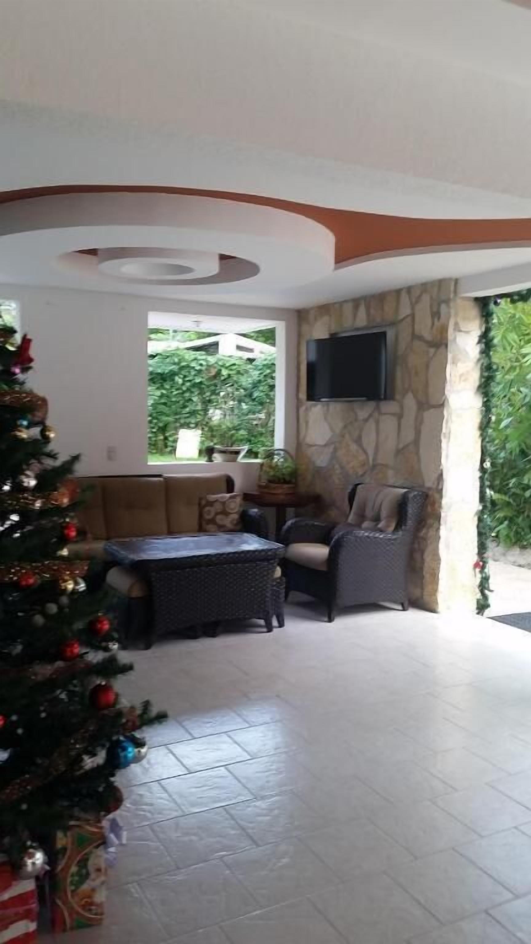 A living room with a stone wall, a flat-screen TV mounted above a fireplace, a Christmas tree, and a sofa.