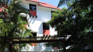 A building with a red roof and white walls, a stone-paved entrance, and a decorative metal gate. - Hotel Cañada Internacional (Palenque)