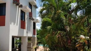 A modern building with a flat roof, multiple windows, and a concrete courtyard. - Hotel Cañada Internacional (Palenque)