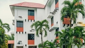 A modern building with a swimming pool, palm trees, and outdoor seating. - Hotel Cañada Internacional (Palenque)