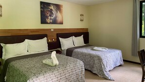 A hotel room with two beds, a wooden headboard, a painting on the wall, and a window with curtains. - Hotel Cañada Internacional (Palenque)