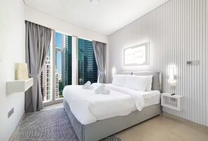 Relax in a spacious room with a large bed, nightstand, and window offering a view of high-rise buildings.