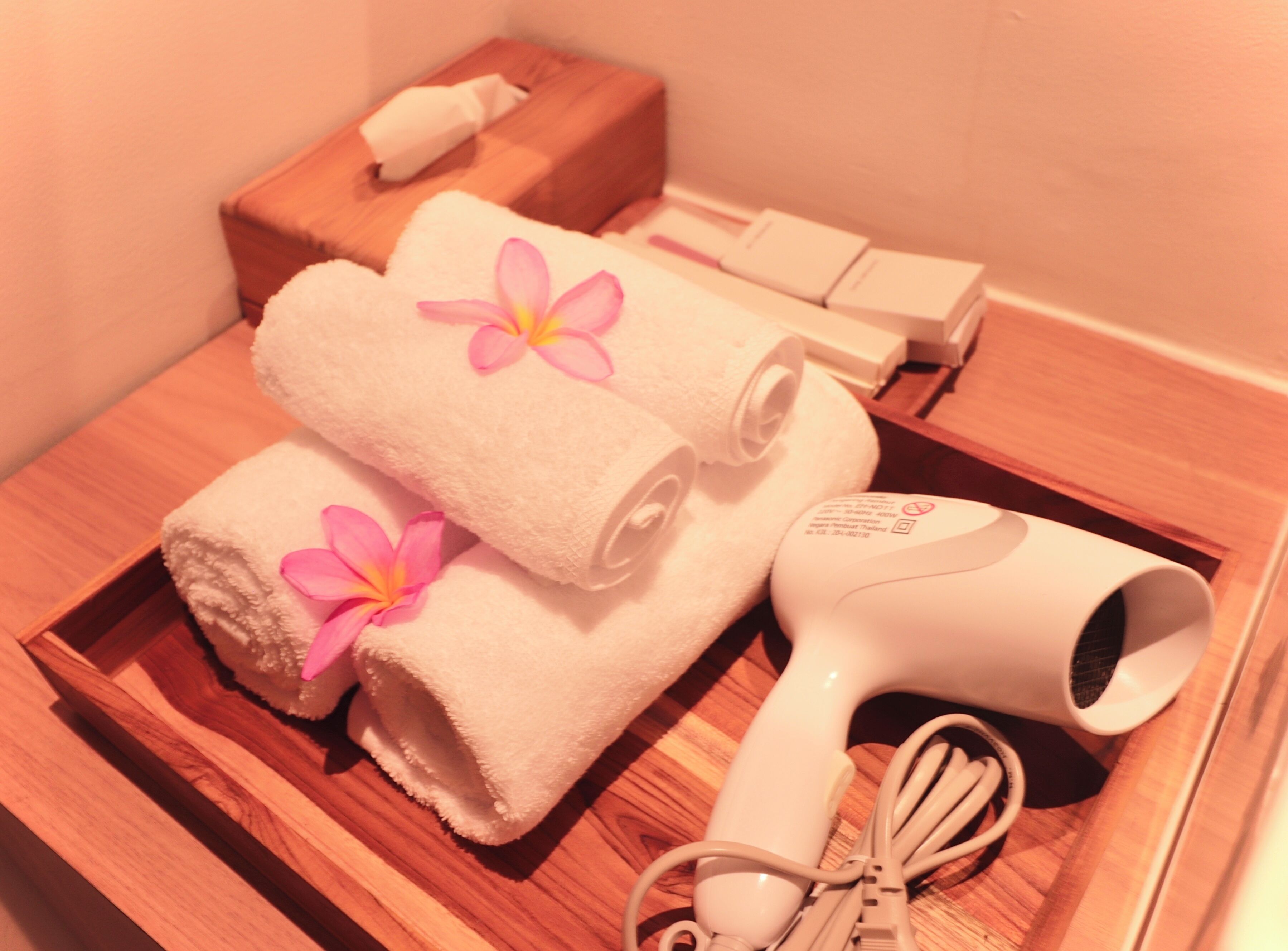 A wooden tray with towels, a hair dryer, and a box of tissues.